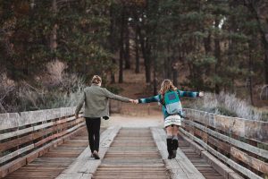 A couple walking across a bridge hold hands for a Birksun lifestyle photo shoot