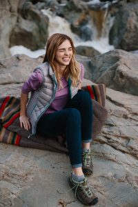 Colleen Cole laughing while sitting on a blanket for a hiking lifestyle photoshoot.