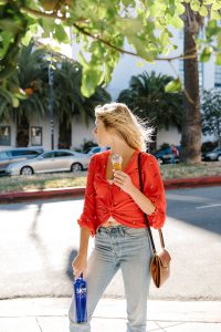 Model holding an ice cream in one hand and a blue SKYY Vodka bottle in the other outside on a street corner in the heart of the Mission
