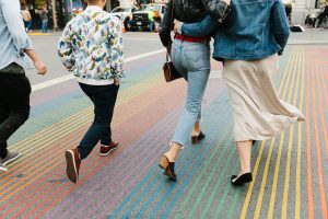 Four people walking across 18th and Castro Street intersection with the rainbow painted crosswalk in the foreground