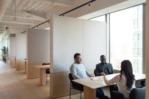 Three employees having an engaging and lively meeting at one of the tables in the office of Turn River Capital, a local private equity firm.