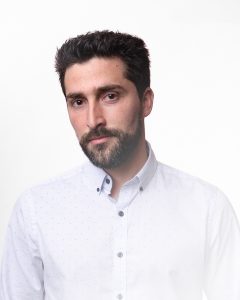 Serious headshot of Paul Flores in a studio with a white backdrop.