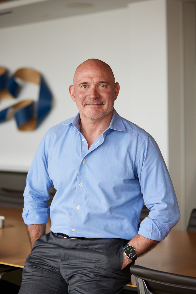 Main post partners employee sitting in a conference room with a confident yet relaxed demeanor captured during a photoshoot