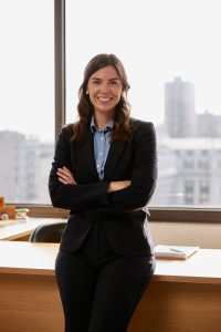 Environmental portrait of Jordan Isern, an associate at litigation law firm Girard Sharp, smiling and leaning against a desk.
